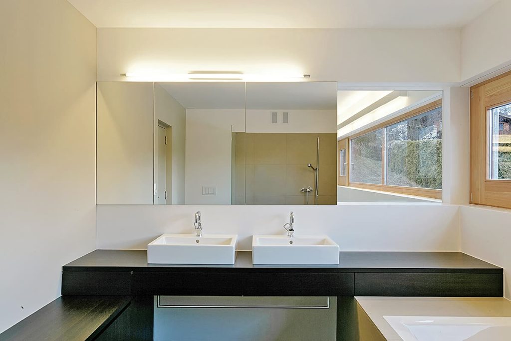 Badmöbel mit schwarzer Waschtischplatte, zwei Aufsatzbecken und grossem Spiegelschrank neben Holzfenster