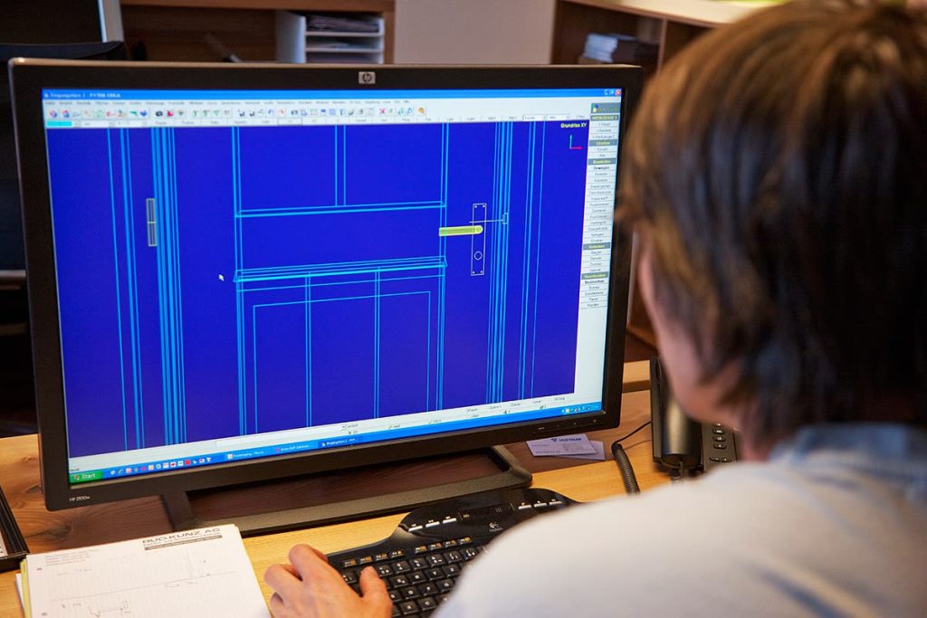 CAD-Zeichnung einer Tür auf dem Bildschirm, Mitarbeiter am Arbeitsplatz von hinten