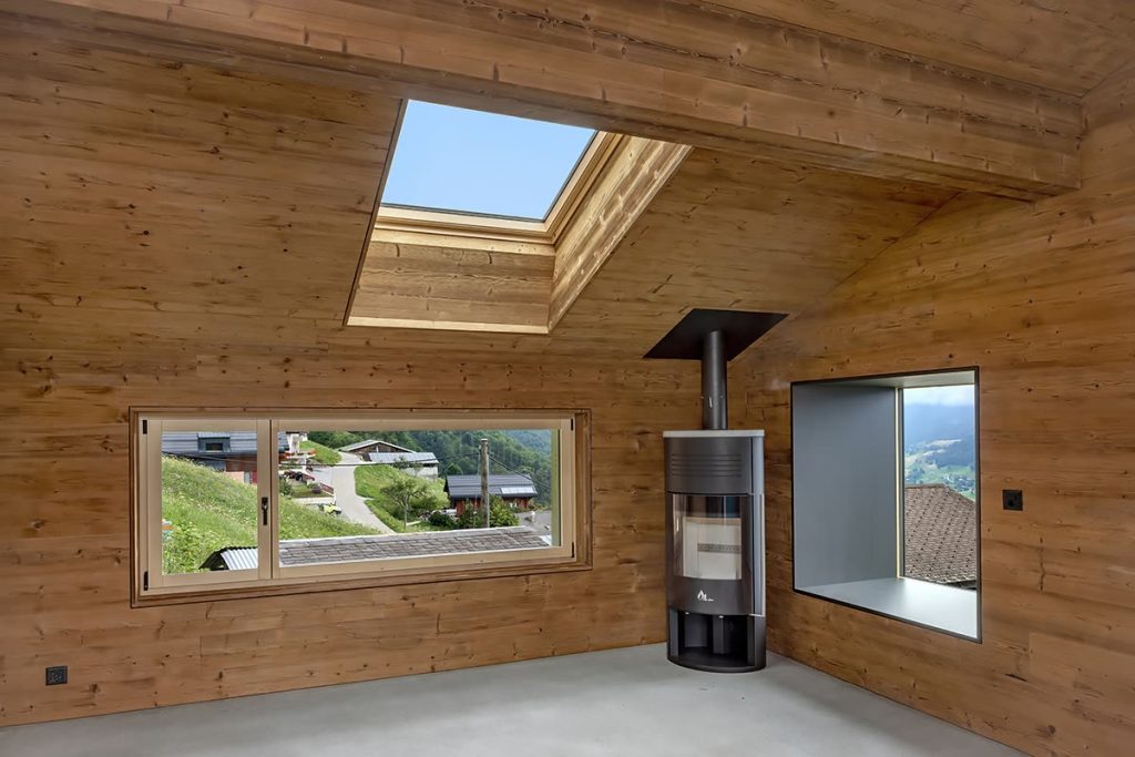 Wohnraum mit Wandverkleidung aus Holz, Dachfenster, Kaminofen und Fensternische