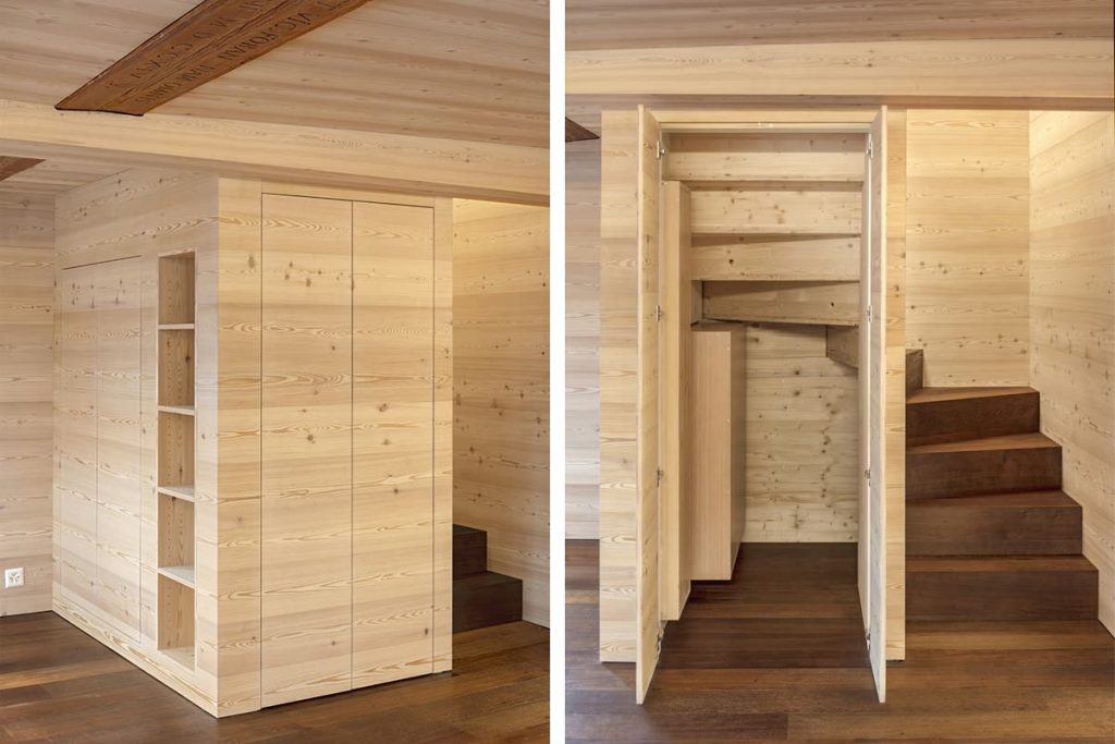 Einbauschrank mit Regal in Holzwand und geöffnete Tür zu Treppe im Untergeschoss