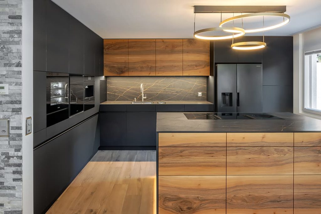 Schwarze Küche mit Nussbaum-Fronten, Kochinsel, Geräteschrank und Ringleuchten
