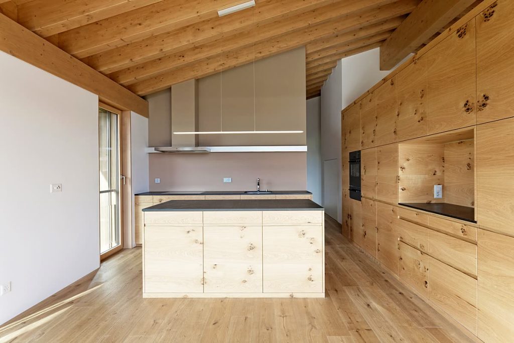 Küche mit astreichen Holzfronten unter der Dachschräge und Einbauschrankwand mit Nische