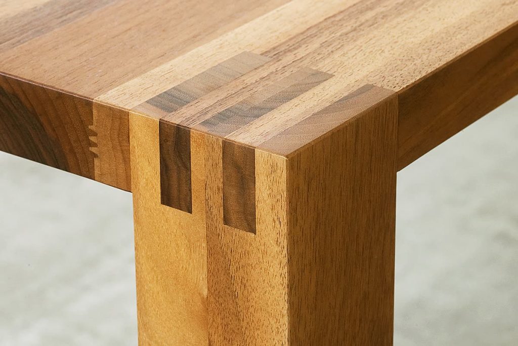 Detail einer massiven Tischecke mit Fingerzinken aus hellem und dunklem Holz