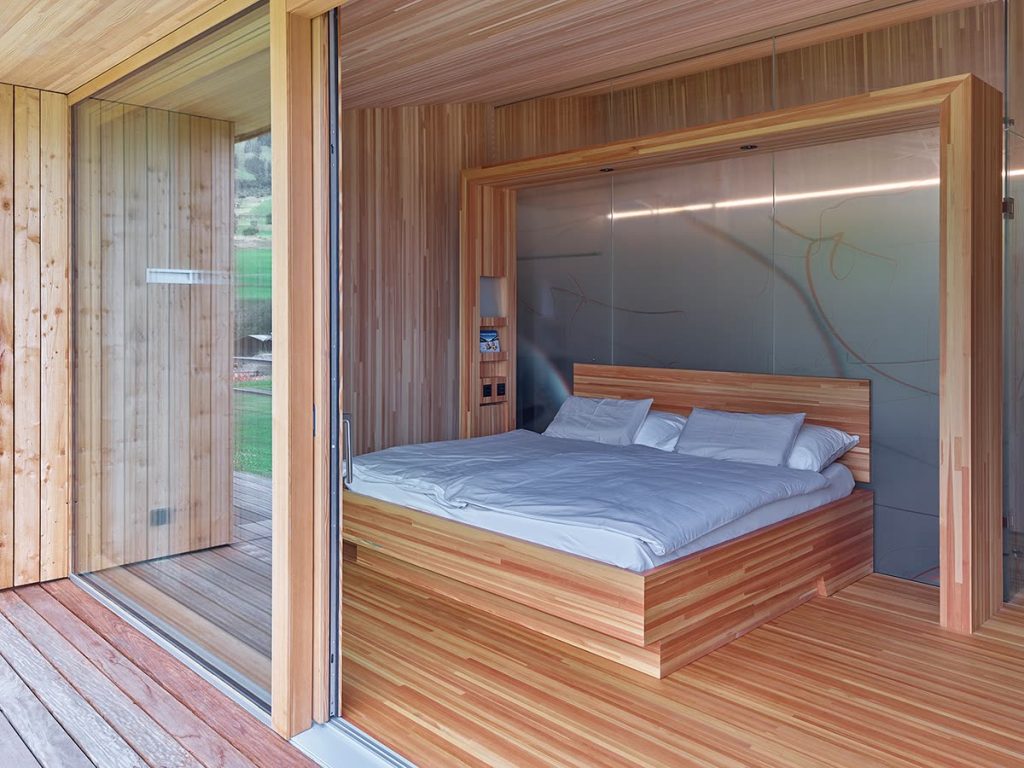 Hotelzimmer mit Holzbett in einer Wandnische aus Holz und Zugang zur Terrasse