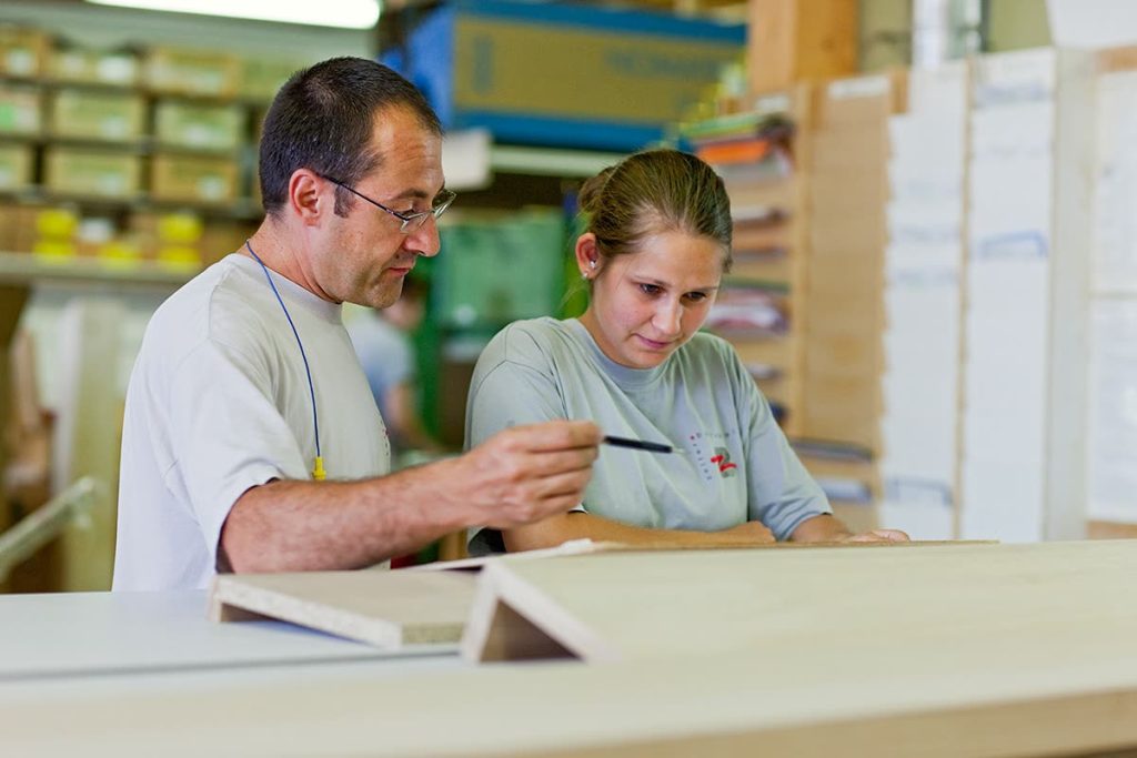 Zwei Mitarbeitende besprechen ein Werkstück an der Werkbank